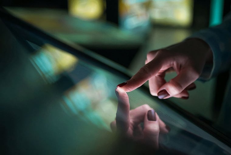 Foto de uma mão tocando uma tela touchscreen