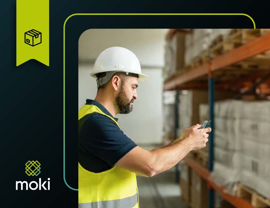 Operador logístico utilizando coletor de dados para estoque Moki para registrar movimentação de palete em armazém organizado.